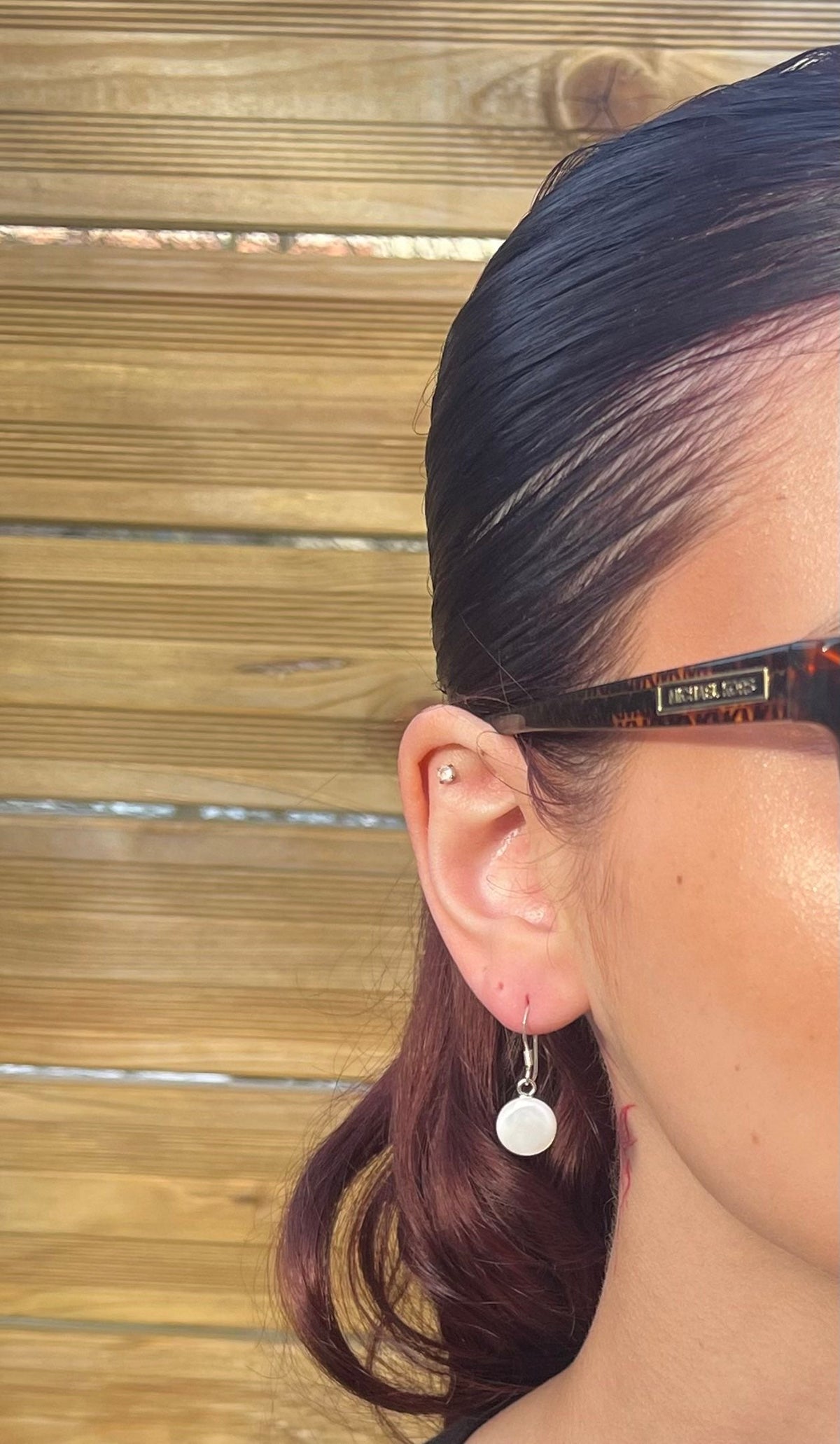 Petites boucles d'oreilles rondes en nacre naturelle portées